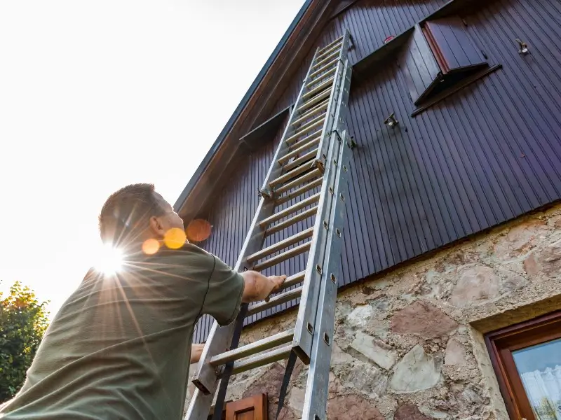 Roofer climbing the tall ladder for roof inspection in Charlotte, NC